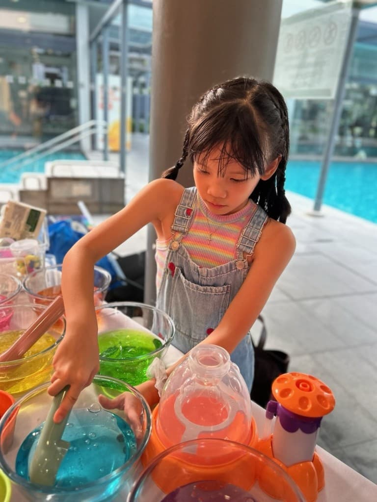 Girl stirring colourful squishy filling at a Glello squishy-making station