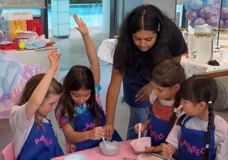 A Glello host guiding children through a hands-on workshop wearing GLELLO aprons